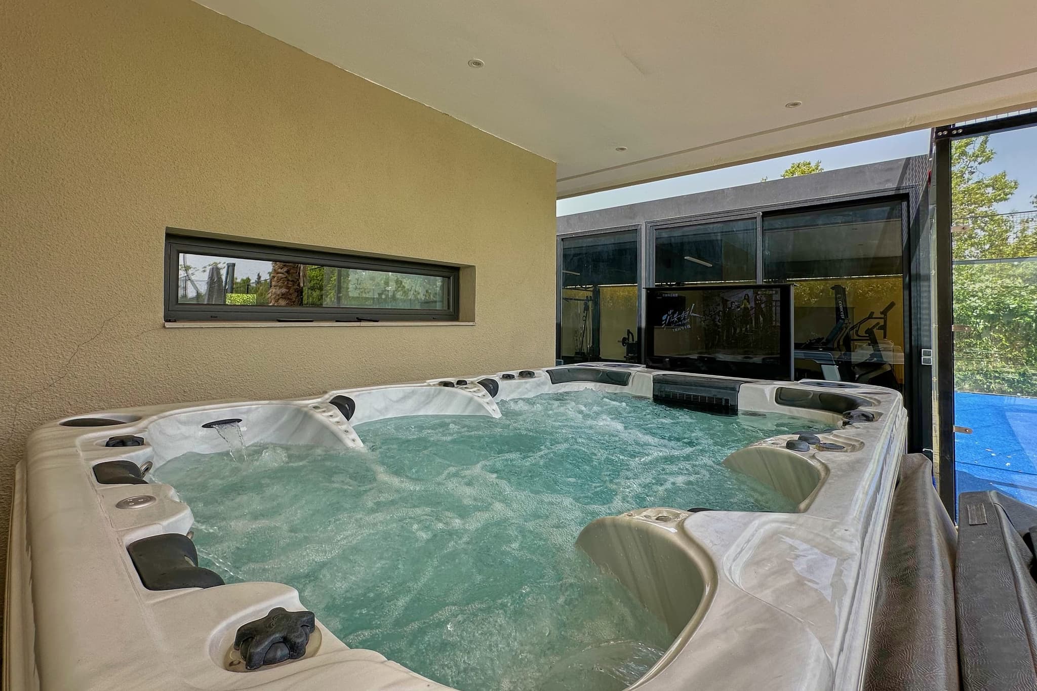 Le spa de nage en eau vive, ouvert sur la salle de sport par une baie vitrée.