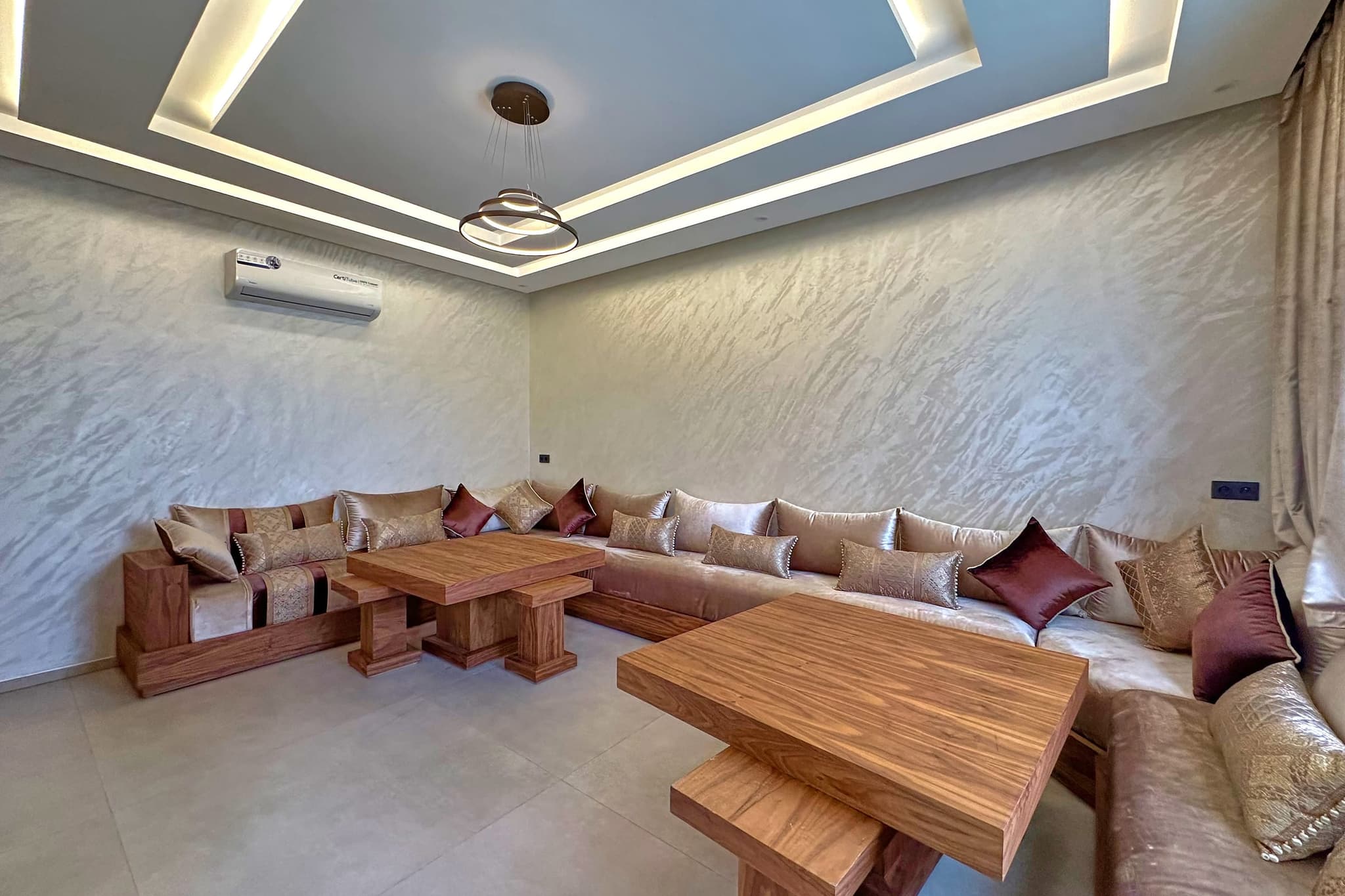Le salon marocain : banquettes basses en L garnies de coussins, deux tables basses en bois massif.